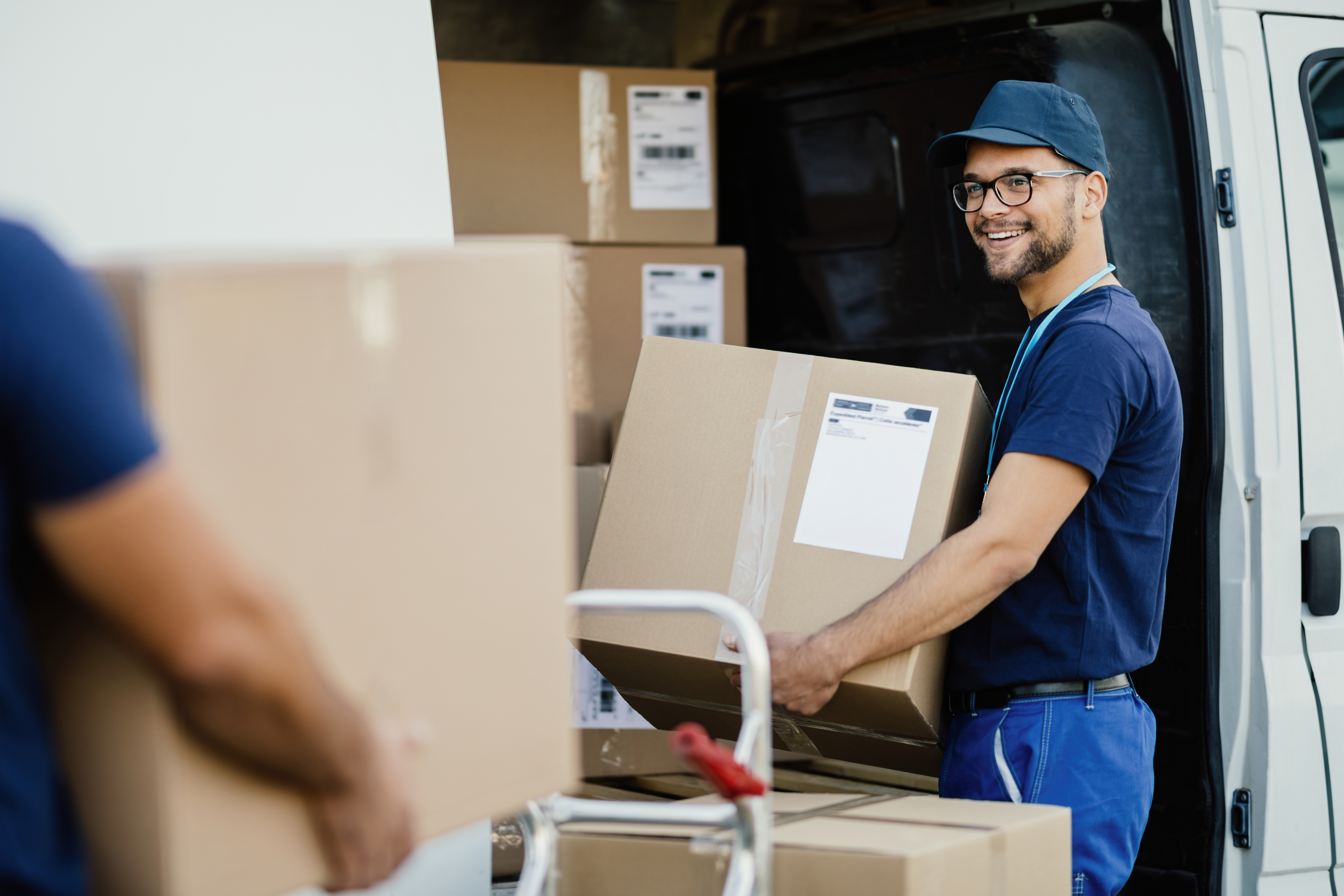 happy-delivery-man-talking-with-coworker-while-loading-boxes-in